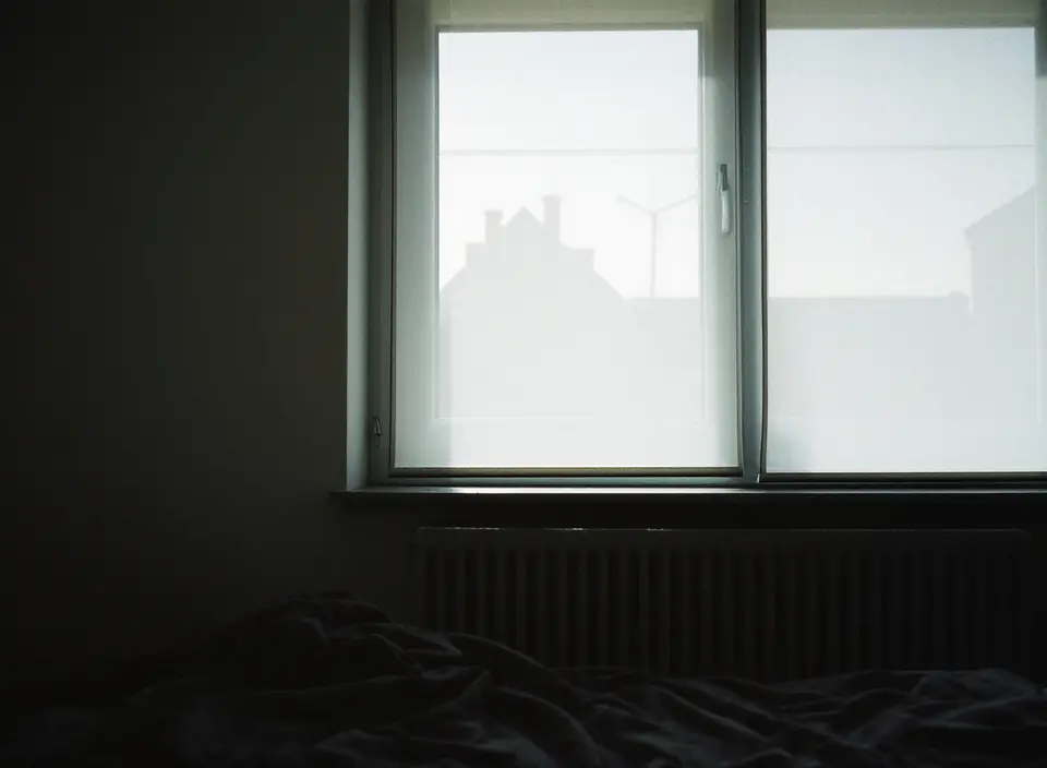 Slaapkamer met gedempt licht doordat een screen aan de buitenkant voor het raam hangt
